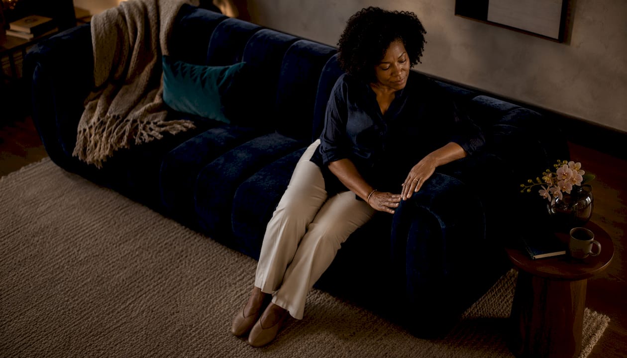 Woman sitting on teal statement sofa in living room