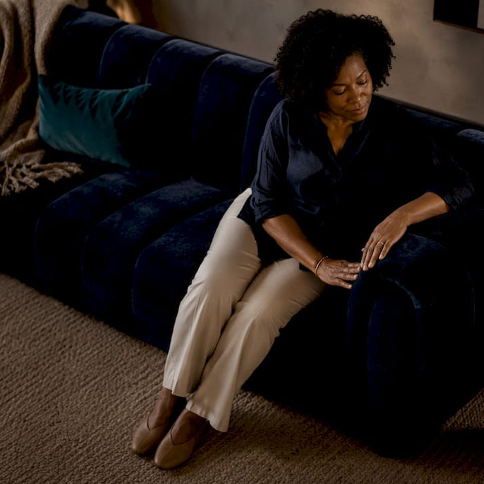 Woman sitting on teal statement sofa in living room