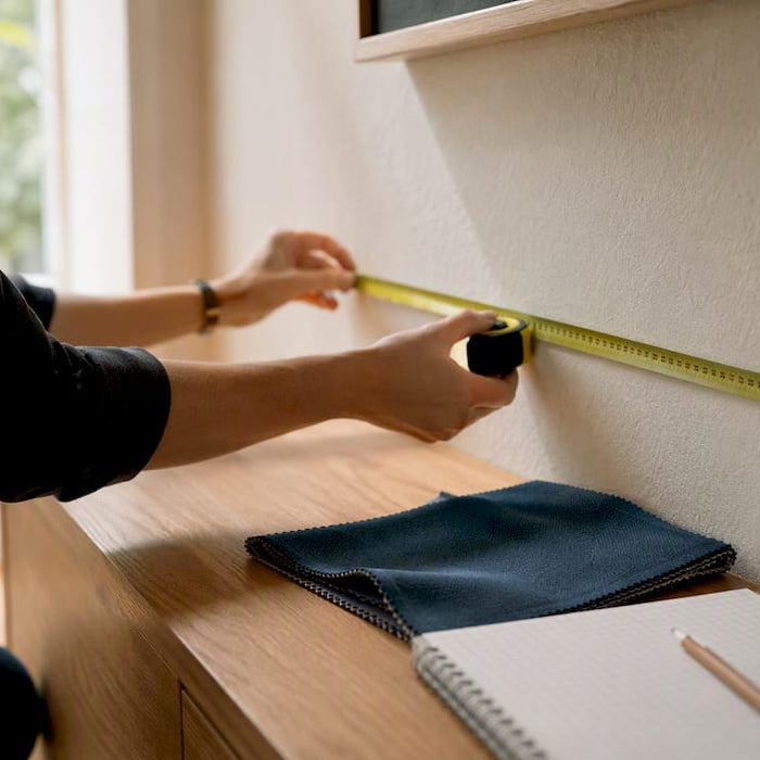 Hand measuring wall with tape measure