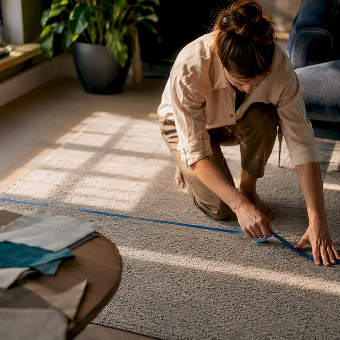 Hands taping sofa footprint on living room floor