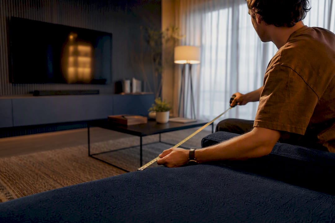 Person measuring sofa to TV distance