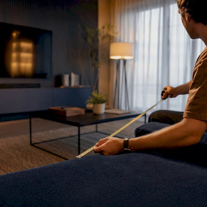 Person measuring sofa to TV distance