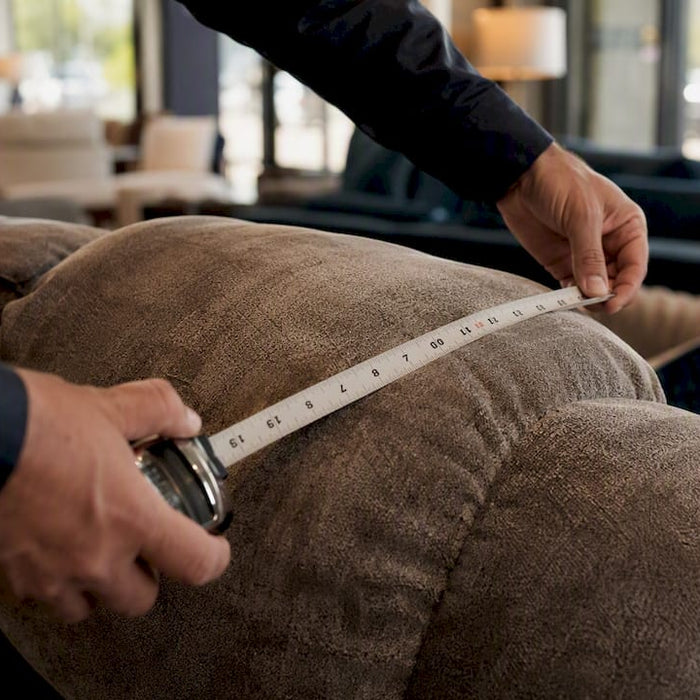 Hands measuring sofa seat depth with tape