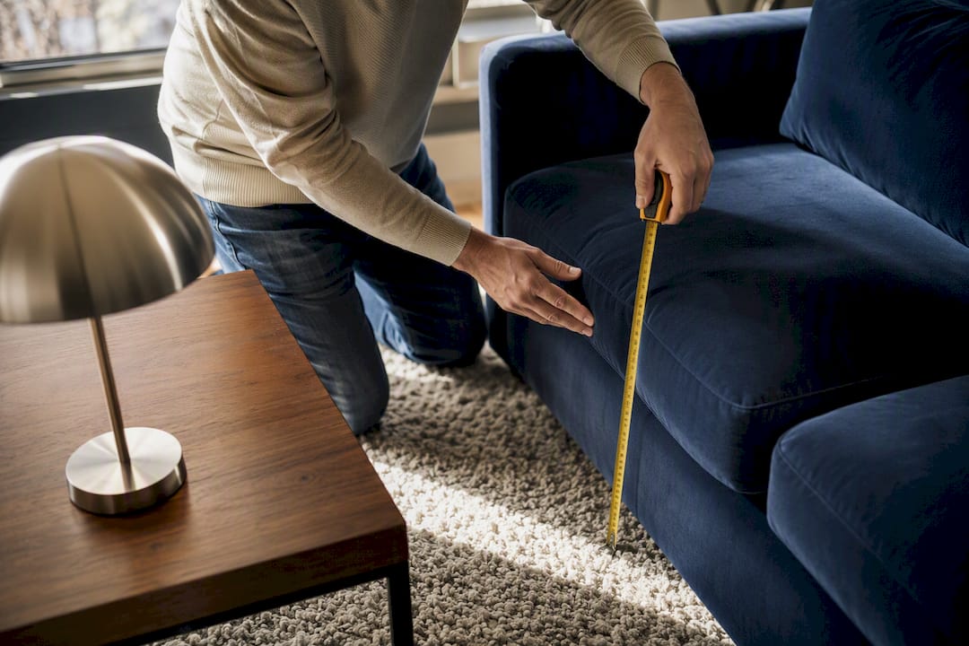 Hands measuring seat height of sofa