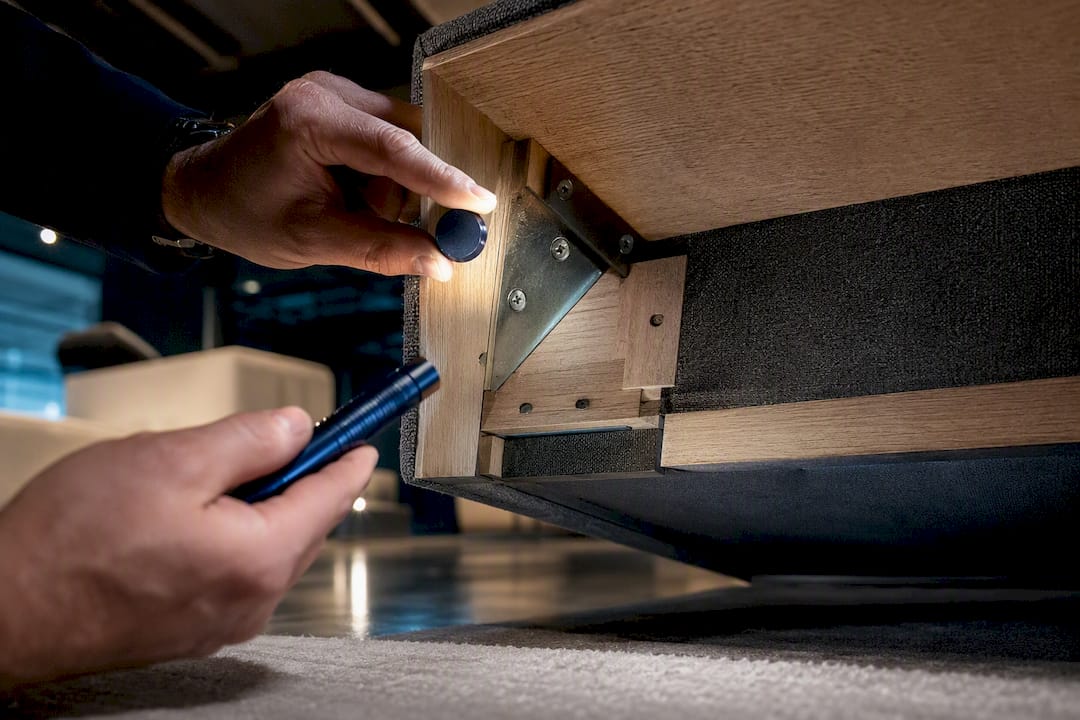 Hands inspecting hidden furniture frame materials