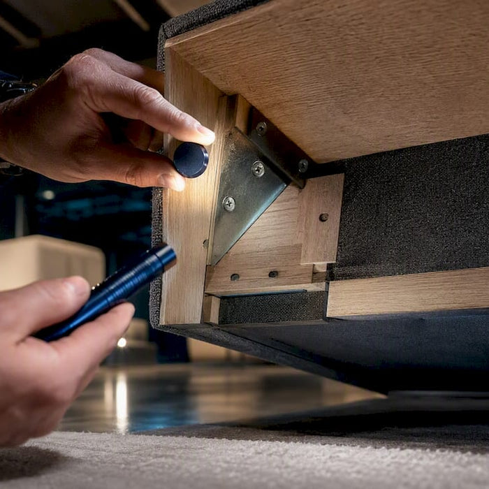 Hands inspecting hidden furniture frame materials