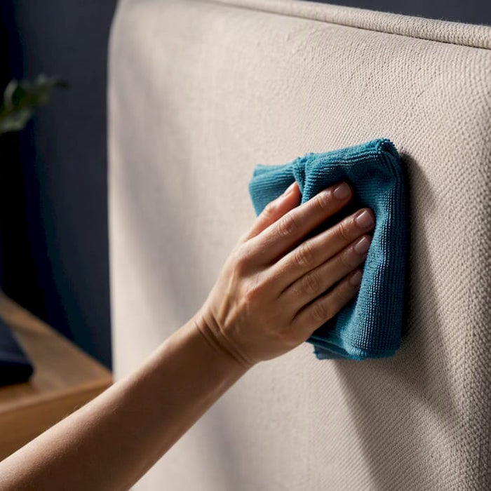 Hand cleaning upholstered headboard with damp cloth